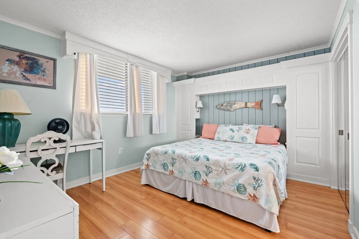 A cozy queen bedroom is shown with a patterned quilt, calming fish wall décor, and a side table with a lamp. The space exudes a peaceful atmosphere, perfect for unwinding after a day spent outdoors.