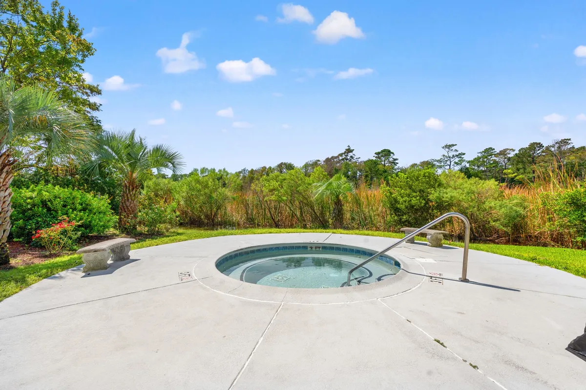 A serene hot tub is nestled among lush greenery, offering a tranquil spot to unwind. The surrounding environment is peaceful, suggesting relaxation and the opportunity to soak in warm, soothing waters at any time of day.