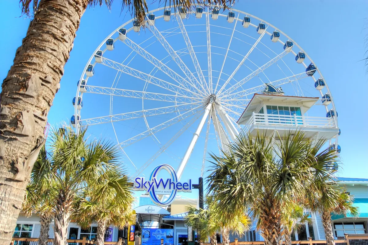The iconic SkyWheel rises above palm trees and an entrance plaza, exuding excitement and local flavor. The vibrant scene captures a must-visit attraction just a stroll away from the property, inviting family outings and shared adventures.